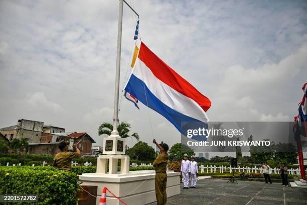 Workers of the Dutch war cemetery raise the flag of the Netherlands during a ceremony marking the 83rd anniversary of the Battle of the Java Sea at...