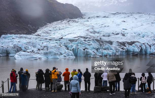 Tourists visit the Vatnajokull Glacier, where the glacier meets the mainland and the lake it forms, highlighting the effects of global warming as it...