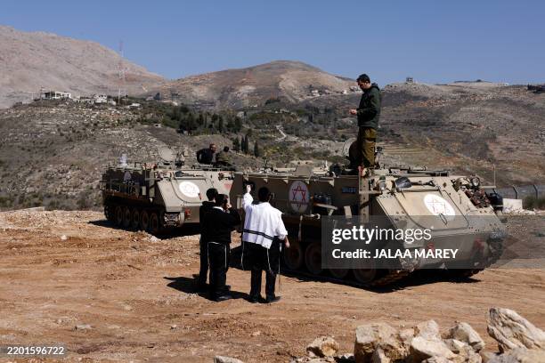Ultra-Orthodox Jewish men speak to soldiers standing on an armoured personnel carrier in the buffer zone which separates the Israeli-annexed Golan...