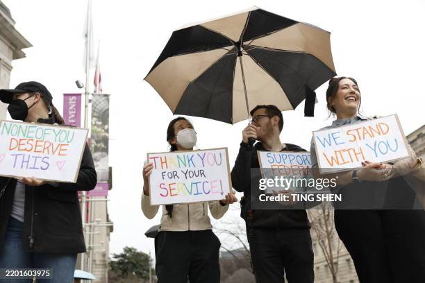 Protestors hold signs as people gather outside the Ronald Reagan Building during a "clap out" in support of United States Agency for International...