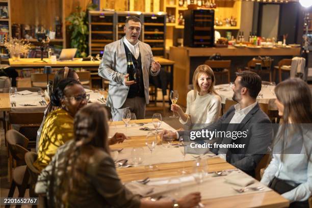 multiracial group of people sitting in luxury restaurant - sommelier stockfoto's en -beelden