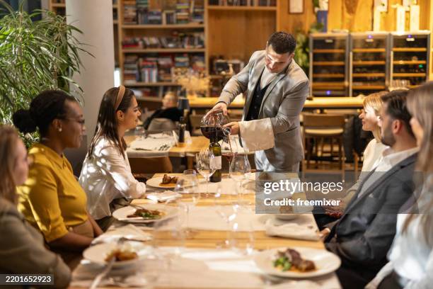 multiracial group of people tasting wine in luxury restaurant - sommelier stockfoto's en -beelden
