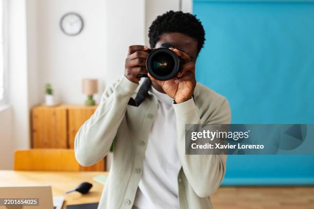 young photographer male taking pictures with digital camera in modern studio - fotógrafo fotografías e imágenes de stock