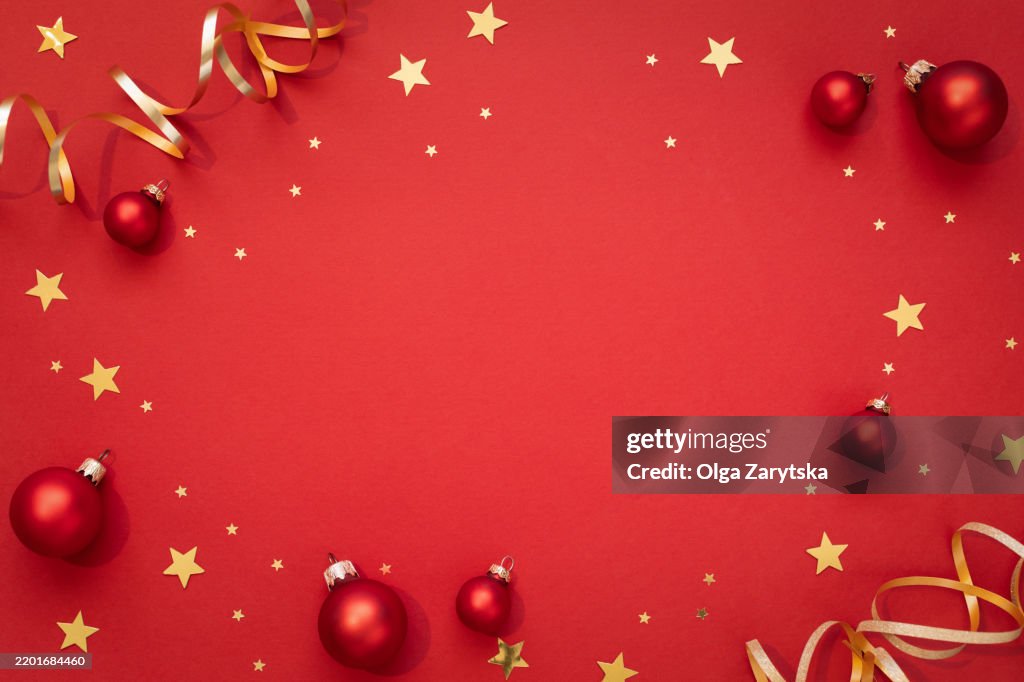 Red Christmas background with red baubles and golden confetti.