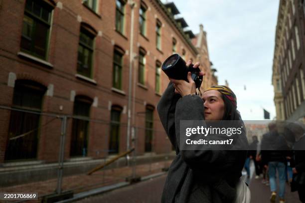 young photographer capturing urban architecture in amsterdam - photographer stock pictures, royalty-free photos & images