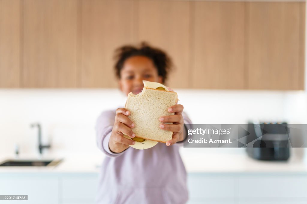 Mixed Race Girl Enjoying Homemade Sandwich in Modern Kitchen