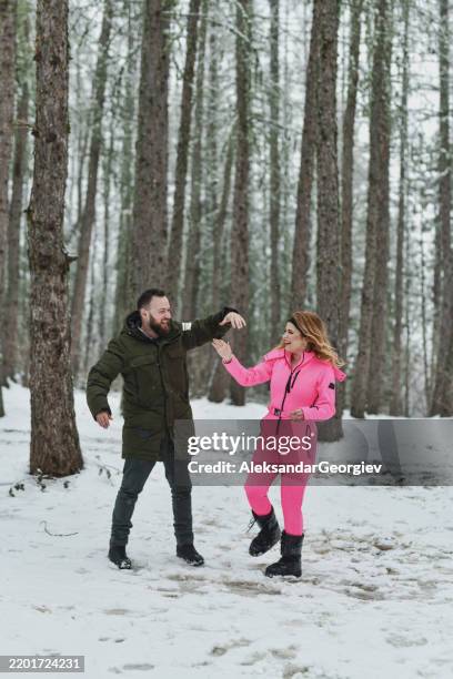 playful couple dancing and having fun in snowy forest - couple dancing twirling stock pictures, royalty-free photos & images