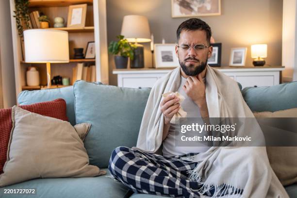 young man with a runny nose and cold symptoms - cold virus stock pictures, royalty-free photos & images
