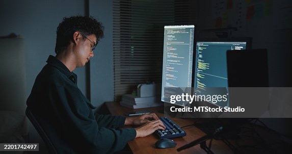 Young man software engineer overwork fall asleep on desk while working late on AI prompts code on computer in bedroom at home night. Software developer, artificial intelligence and programmer. Young man software engineer overwork fall asleep on desk while working late on AI prompts code on computer in bedroom at home night. Software developer, artificial intelligence and programmer.