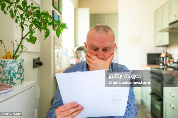 worried mid adult man checking bills at home - only men stock pictures, royalty-free photos & images
