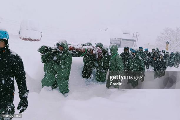In this handout photo taken and released by the State Disaster Response Force on February 28 rescuers carry Border Roads Organisation workers after...