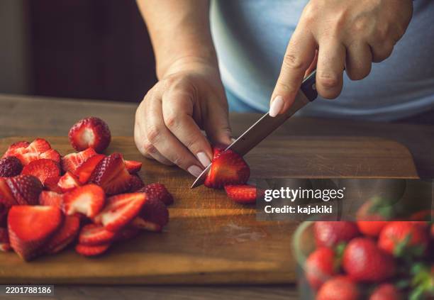 mujer cortando fresas frescas - fresa fotografías e imágenes de stock