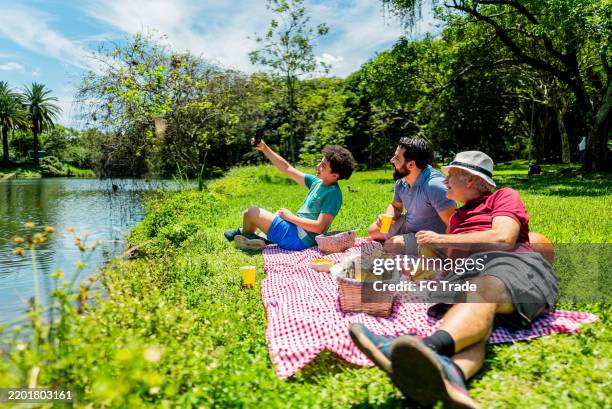 family taking selfie during picnic in a public park - ibirapuera park stock pictures, royalty-free photos & images