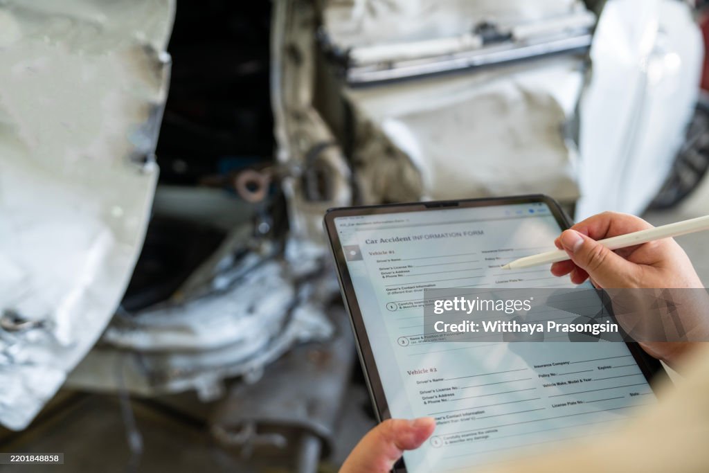 Person Completing Accident Form on Tablet by Damaged White Car
