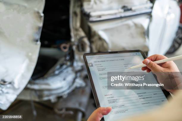 person completing accident form on tablet by damaged white car - antragsformular stock-fotos und bilder