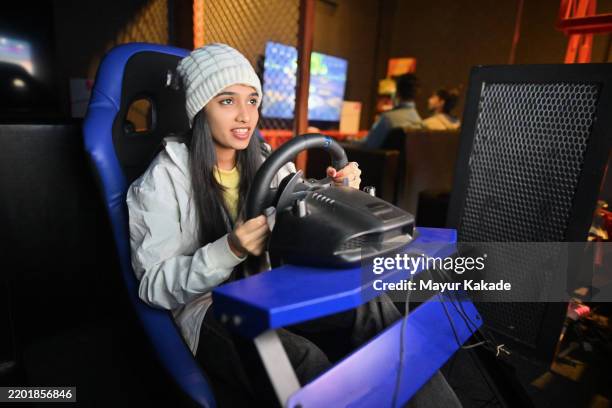 junges mädchen genießt ein spannendes autorennspiel in einem gaming-hub - simulator stock-fotos und bilder