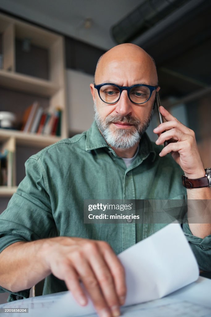 Professional Man on Phone Analyzing Documents in Office Setting