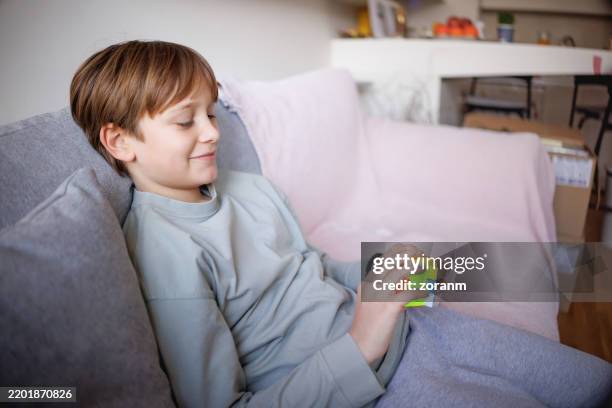 boy sitting on the sofa at home and playing with puzzle cube - rubiks kub bildbanksfoton och bilder