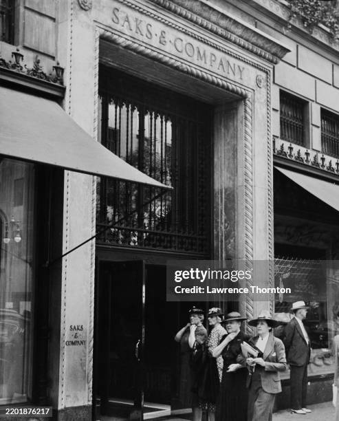 View of four women walking past the entrance of the Saks & Company luxury department store on Fifth Avenue, New York, 1940s.