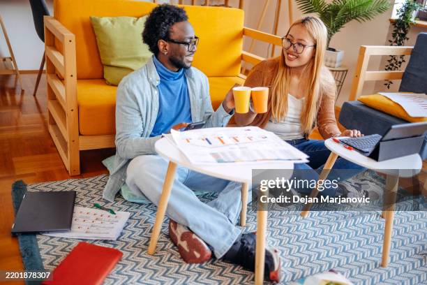 university students spending time studying together at home using wireless technology and charts - roommate stock pictures, royalty-free photos & images