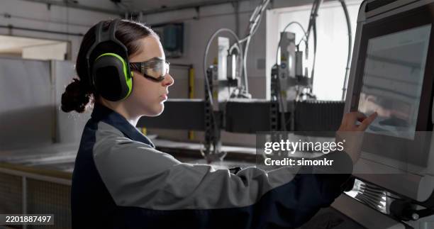 young adult female operating cnc water pressure cutting machine - ear defenders stock pictures, royalty-free photos & images