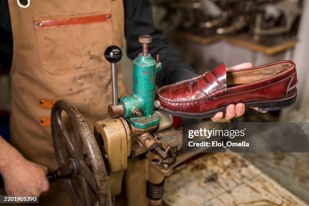 skilled craftsman repairing vintage red leather loafer using traditional shoe restoration machinery, highlighting meticulous handwork within compact workshop setting - vintage hand tools stock pictures, royalty-free photos & images
