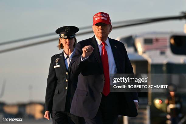 President Donald Trump raises a fist as he walks to board Air Force One as he departs Joint Base Andrews in Maryland on February 28 en route to his...