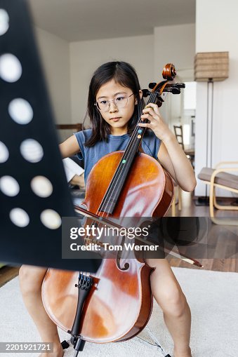 Young Girl Practicing the Cello While Reading Sheet Music Young Girl Practicing the Cello While Reading Sheet Music