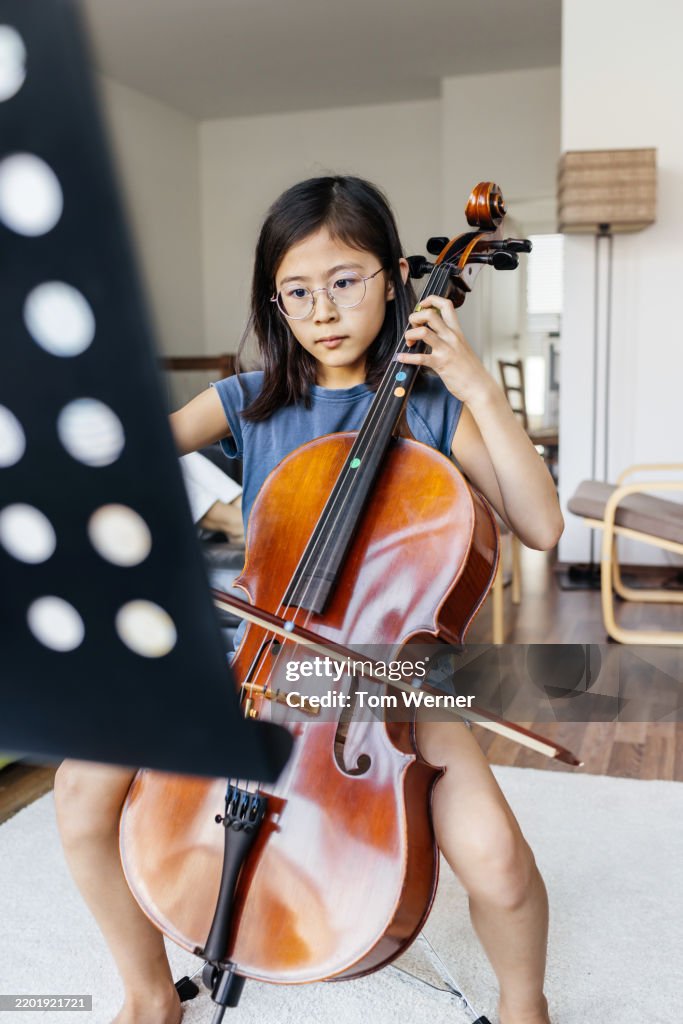 Young Girl Practicing the Cello While Reading Sheet Music