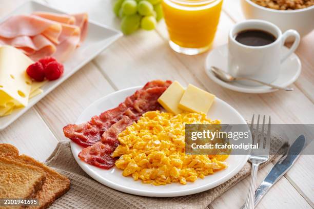 scrambled eggs with bacon plate served on breafast table - spek stockfoto's en -beelden