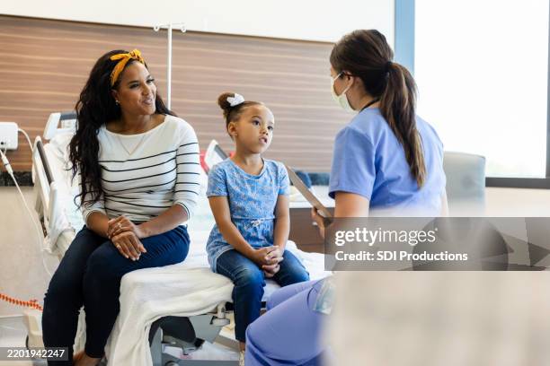 kind und mutter in arztpraxis, medizinisches fachpersonal, sprechend - notfallmedizin stock-fotos und bilder