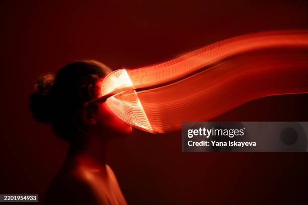 an unrecognizable person doing full body red light therapy in a dark room - luce led foto e immagini stock