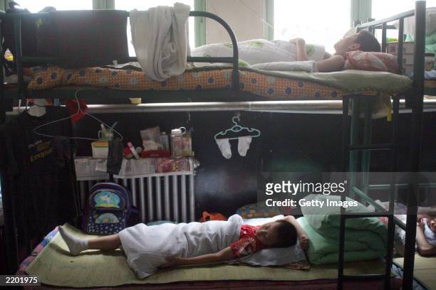 Two students sleep at noon in their dormitory before the beginning of their daily training at the state owned Shichahai sports school July 25, 2003...