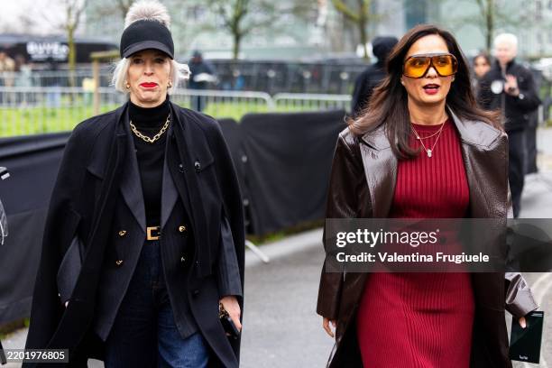 Guest wears on the left a black baseball hat with beige fur, a black turtle neck sweater, a gold chain necklace, a grey blazer, a black coat and blue...