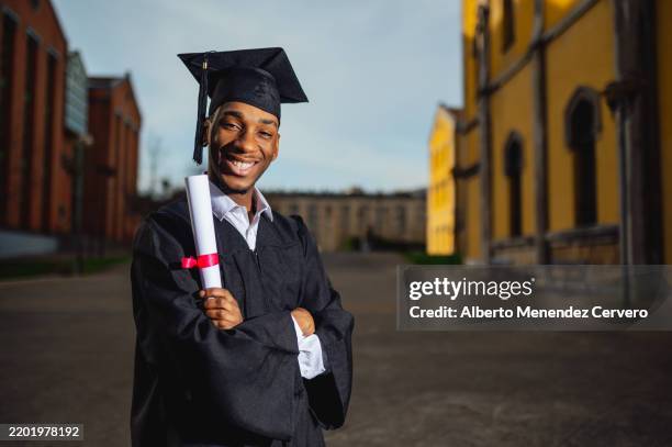 young man celebrating graduation day on university campus - graduation clothing stock pictures, royalty-free photos & images