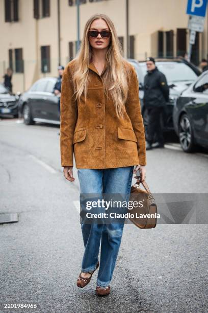 Romee Strijd is seen wearing a brown leather jacket, blue denim pants, sunglasses and brown suede Gucci Blondie bag outside Gucci during the Milan...