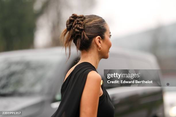 Tamara Kalimic wears gold mini hoop earrings, black cutout draped sheer mesh Gucci dress, outside Gucci, during the Milan Fashion week Men’s...