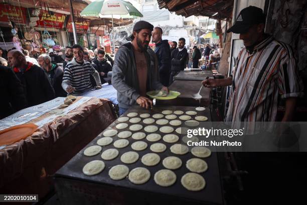 Palestinian bakers prepare a tray of Qatayef, traditional Arabic dumplings, on the first day of the Muslim holy fasting month of Ramadan on March 1,...
