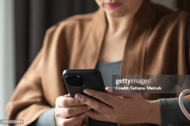 modern woman using smartphone in a cozy home office - hot desking stock pictures, royalty-free photos & images