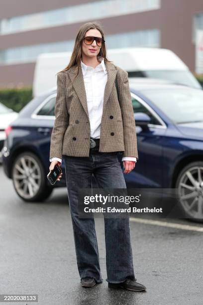 Guest wears black sunglasses, white buttoned up long sleeve shirt, dark brown plaid pattern/print cropped blazer jacket, black leather belt with...