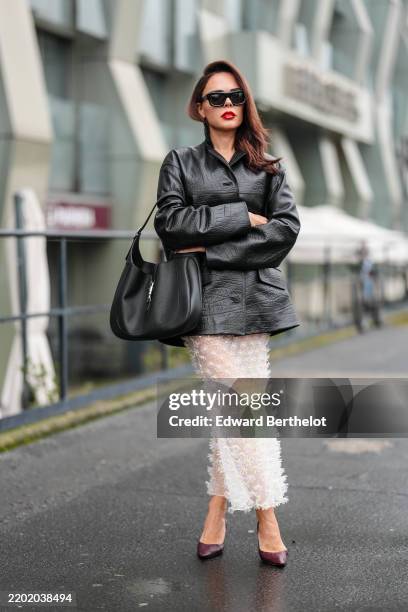 Evangelie Smyrniotaki wears black sunglasses, shiny Gucci leather jacket, shiny Gucci Jackie 1961 leather bag, white sheer mesh daisy midi skirt,...