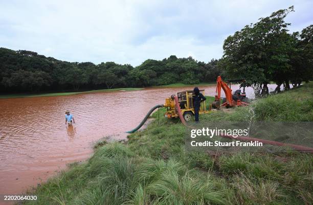 Workers pump water water on the 16th fairway after heavy overnight rainfall left the course flooded prior to the Investec South African Open...