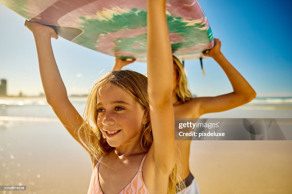 Brother and sister carrying surfboard on sunny australian beach