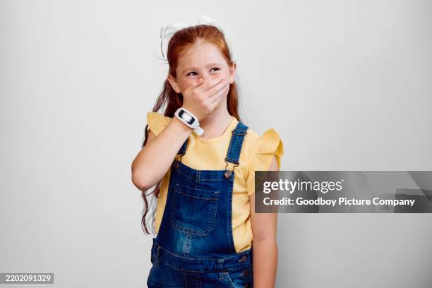 studioporträt eines mädchens mit roten haaren, das den mund mit der hand bedeckt und wegschaut - auf frischer tat ertappt stock-fotos und bilder