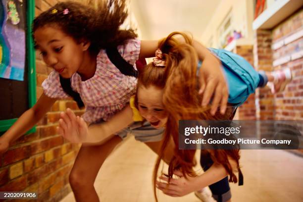 action shot of two school girls falling over in corridor, smiling, blurred motion - careless stock pictures, royalty-free photos & images