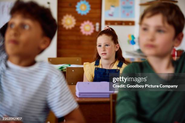 elementary school girl with red hair and pensive expression sitting towards back of class, listening - shy stock pictures, royalty-free photos & images