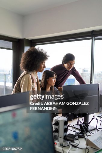 Three programmers collaborating on a computer in a modern office, sharing ideas and strategies while working on software development projects Three programmers collaborating on a computer in a modern office, sharing ideas and strategies while working on software development projects
