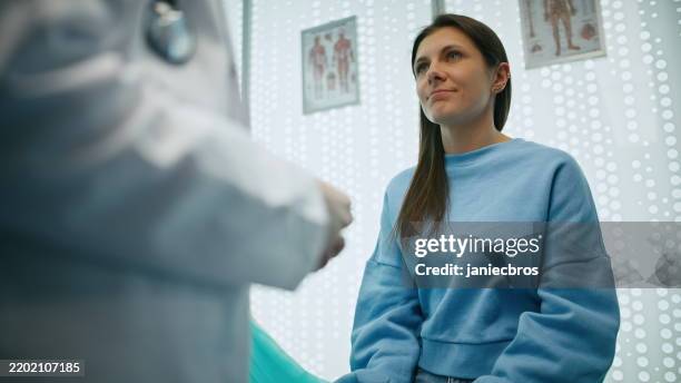 female doctor giving the female patient good news regarding her health status - doctor giving good news stock pictures, royalty-free photos & images