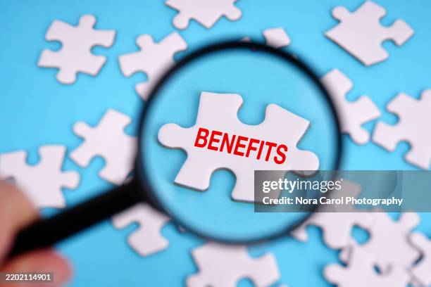 magnifying glass focused on jigsaw puzzle with text benefits - perks stock pictures, royalty-free photos & images