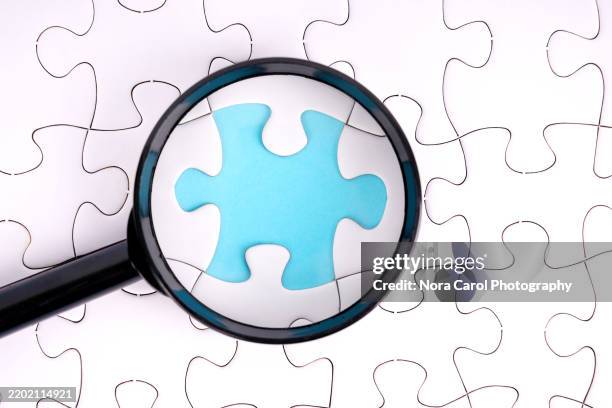 magnifying glass focused on missing jigsaw piece - missing jigsaw piece stock pictures, royalty-free photos & images